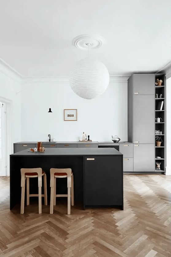 a stylish modern kitchen with white walls and a neutral herringbone floor, grey cabinetry, a black kitchen island