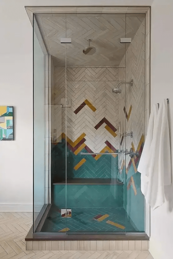 a super creative colorful shower space done with green, burgundy, mustard herringbone tiles and enclosed in glass is amazing