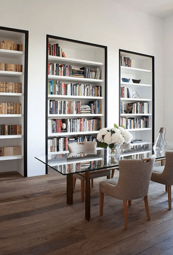 A super refined home office with built in bookshelves with black framing to accent them as much as possible