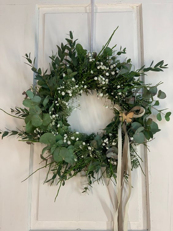 a textural spring wreath covered with greenery and foliage, baby's breath and twigs plus some ribbon is amazing