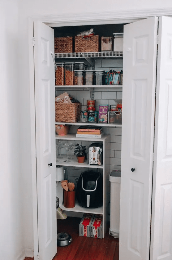 a tiny pantry with open shelves, a subway tile backsplash, cubbies and baskets for storage and some appliances and food