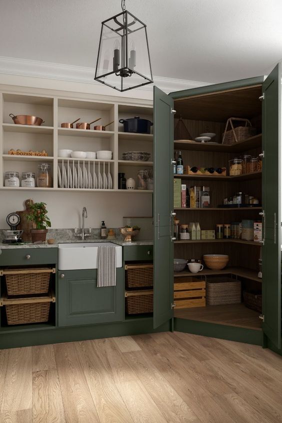 a vintage dark green kitchen with open cabinets and a corner pantry that is perfectly blended into the kitchen decor