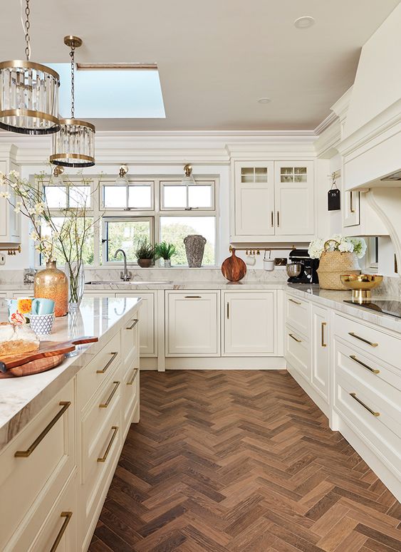 a vintage farmhouse kitchen in creamy shades, with a dark herringbone floor and chic pendant lamps is amazing