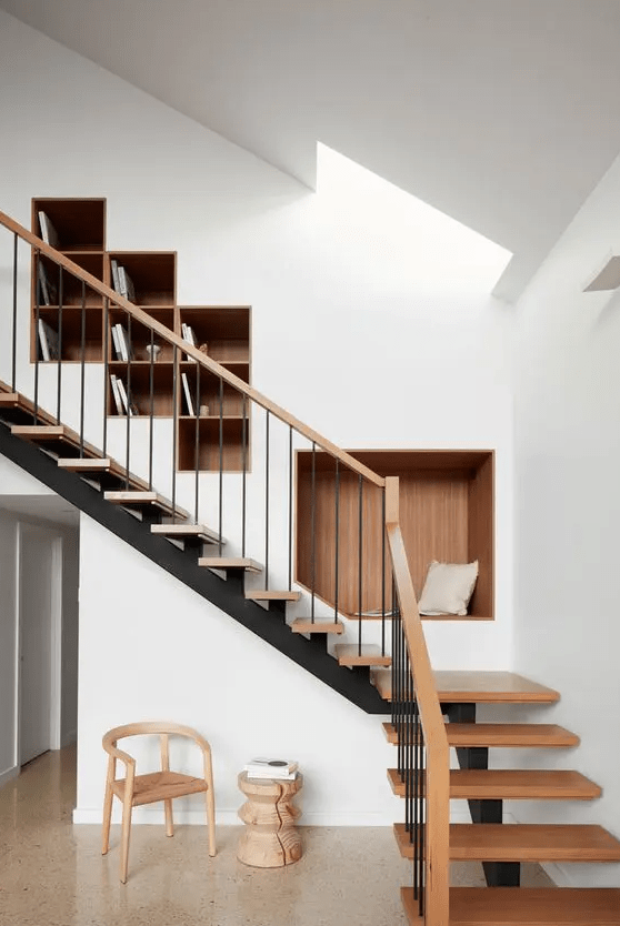 a wall with built-in bookshelves and a niche seat is a genius idea to rock over the stairs