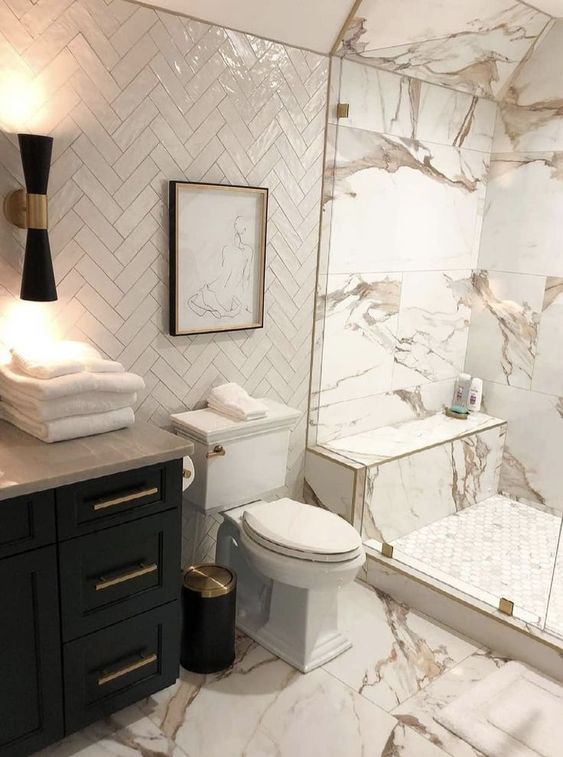 a white bathroom clad with Calacatta marble and white herringbone tiles, with a black vanity and lamp is very refined