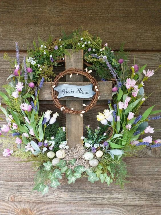 an Easter inspired wreath with greenery and leaves, pink, purple and white blooms, a mini wreath and eggs is cool
