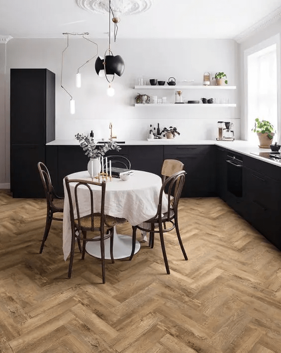 an elegant eat-in kitchen with black lower cabinets, white walls and shelves, a herringbone floor and a vintage dining set