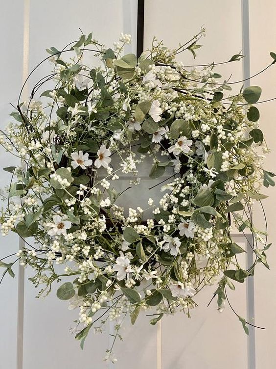 an extra lush and textured spring wreath with greenery and white blooms, twigs and leaves is amazing