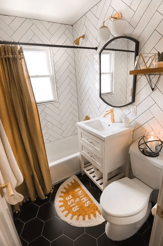 An eye catching bathroom with herringbone tiles and black hex ones, a bathtub, a vanity with a sink, a mustard curtain and a rug