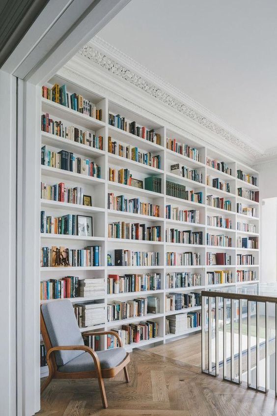 built-in bookshelves covering the whole wall and a grey chair are a lovely combo for any space