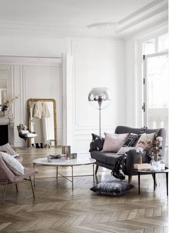 a French chic meets Scandinavian living room with chevron flooring, a grey sofa, a pink chair, a floor lamp and a coffee table