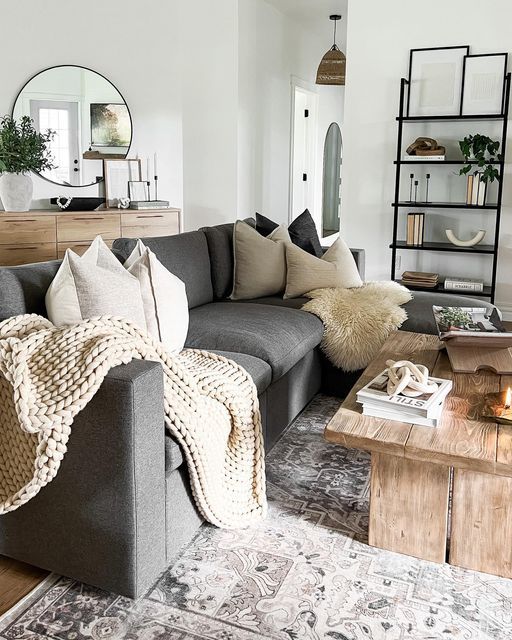 a Scandinavian living room with a grey sofa, a wooden coffee table, a shelving unit, a credenza with a mirror and some lamps