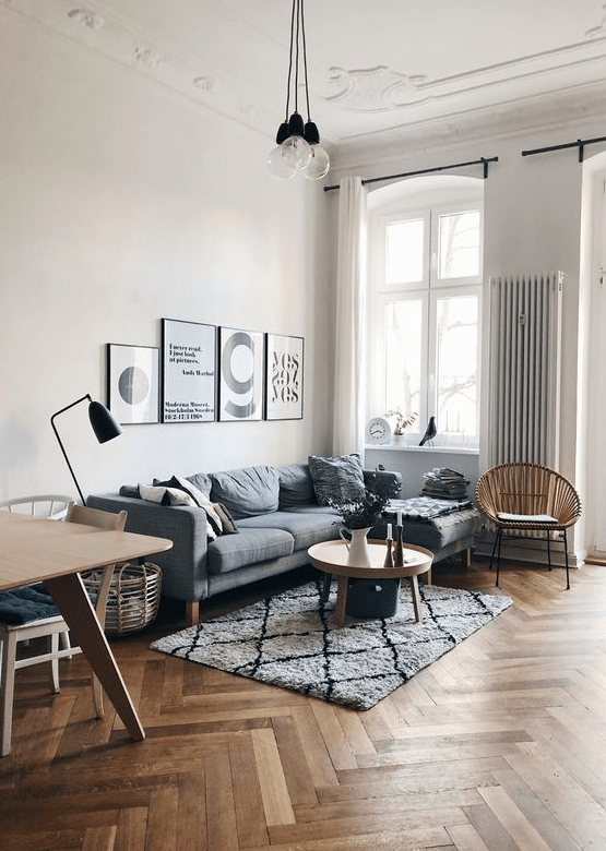 a Scandinavian space with a herringbone floor, a grey sectional sofa, coffee tables, a gallery wall and pendant lamps