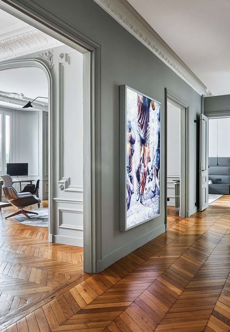 a beautiful Parisian apartmen with grey walls and molding, a chevron floor, some art and super elegant and chic furniture
