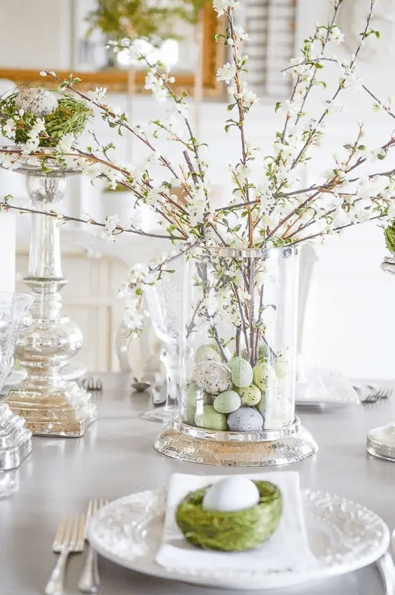 a beautiful and easy spring centerpiece of a large vase with pastel faux eggs and blooming branches is a pretty and chic idea