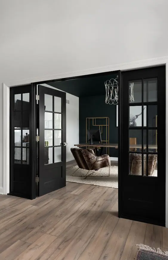 a beautiful and refined space with black glass doors that echo the accent black wall and create a cohesive space