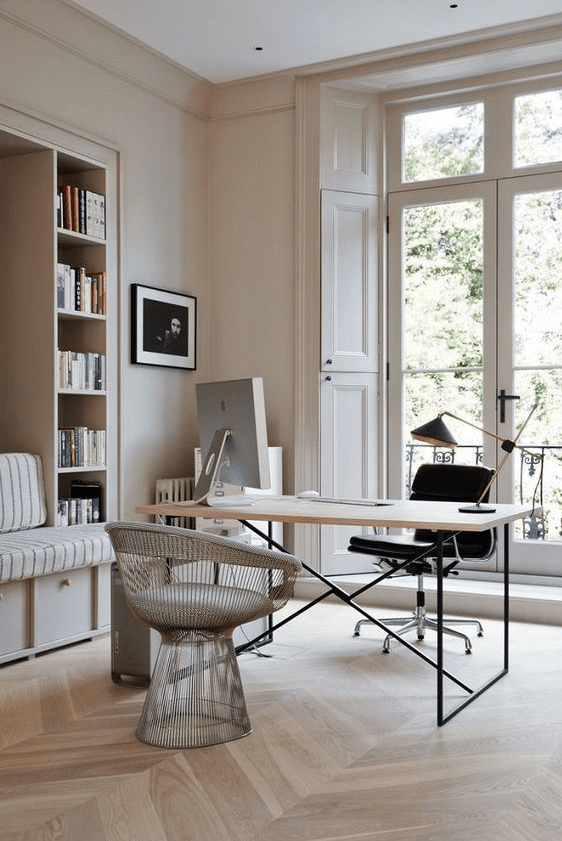 a beautiful neutral home office with built-in shelves and a seat, a desk, a black chair and a neutral one, some decor and books