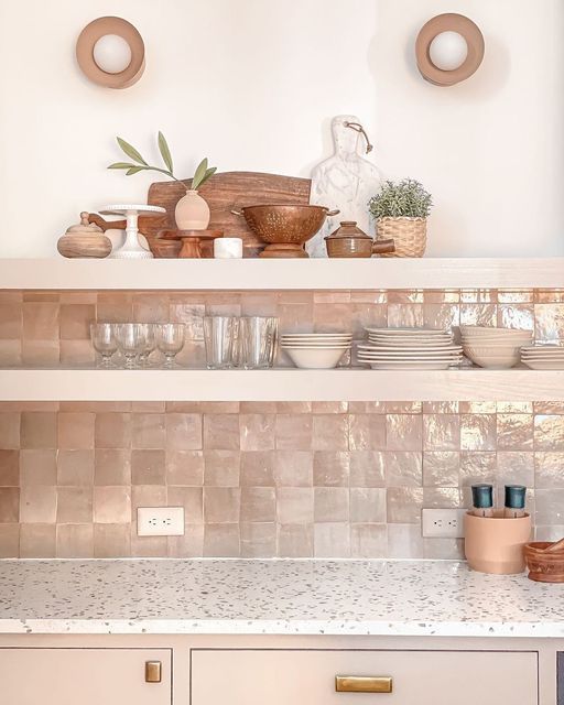 a blush kitchen with terrazzo countertops, a pink Zellige tile backsplash, open shelves for storage and decor