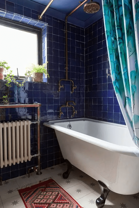 a bold bathroom with shiny electric blue Zellige tiles, a star print tile floor, a clawfoot tub and a bold printed curtain