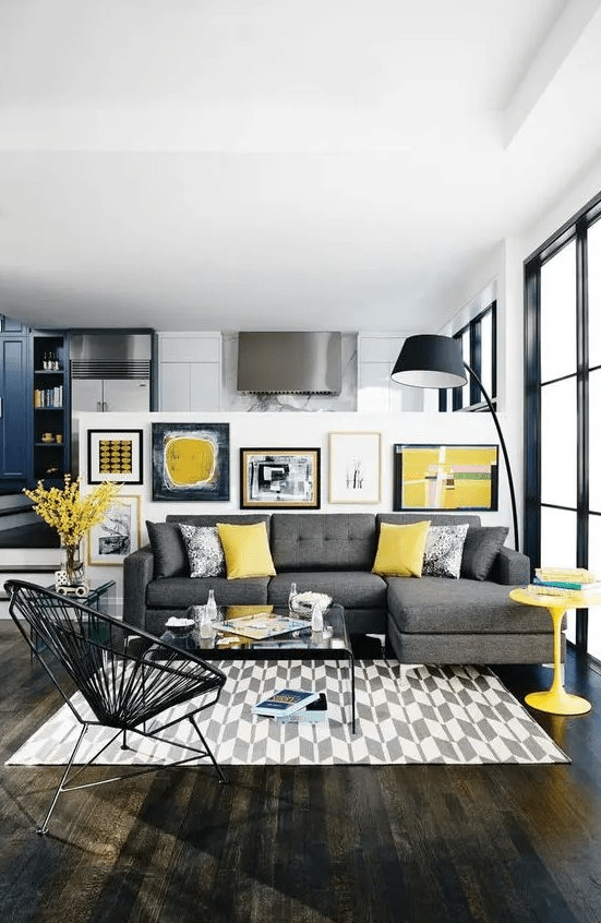 a bold modern living room with a grey sectional, a printed rug, a bright gallery wall, a black floor lamp and a yellow table