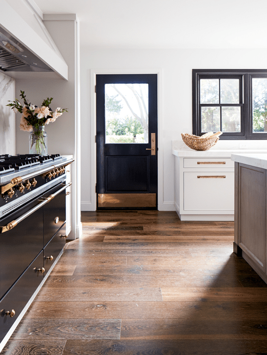 a chic kitchen with a touch of art deco – a black and gold cooker and a matching door and black frame windows