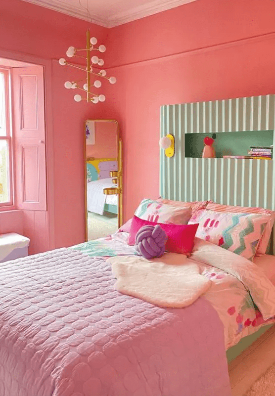 a dopamine decor bedroom with coral walls and shutters, a bed with a mint green headboard, colorful and pastel bedding and a mirror