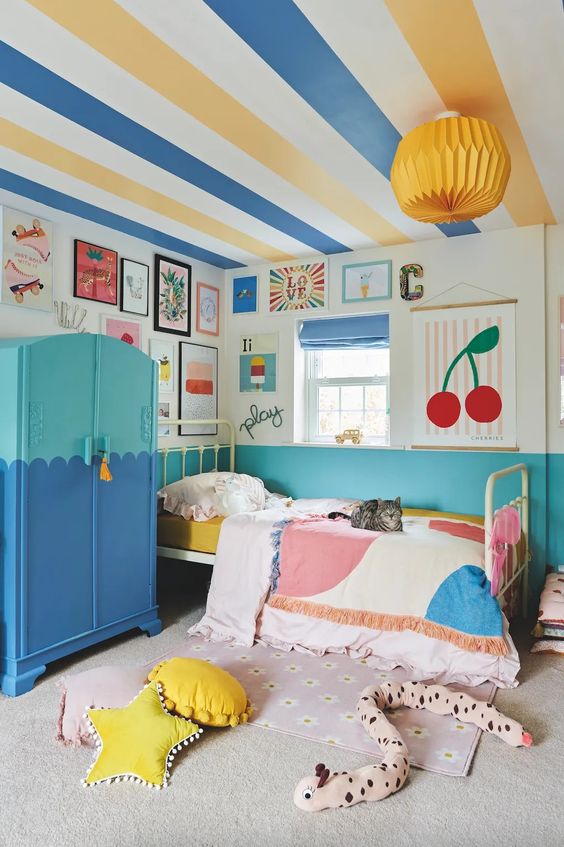 a dopamine decor kid's room with a striped ceiling, a color block wardrobe and walls, a bright gallery wall and textiles