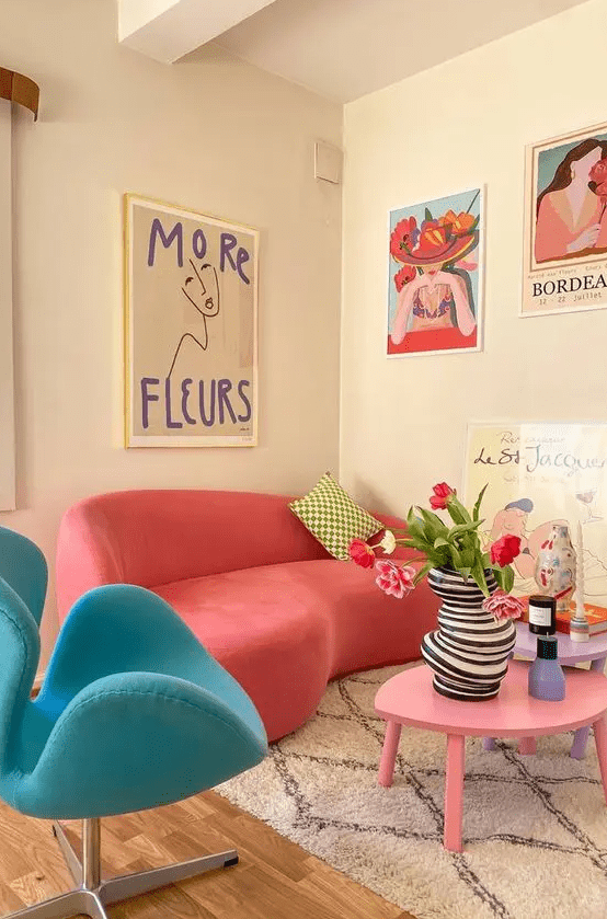 a dopamine decor living room with a coral curved sofa, a blue chair, a pink coffee table, bold artwork and some decor