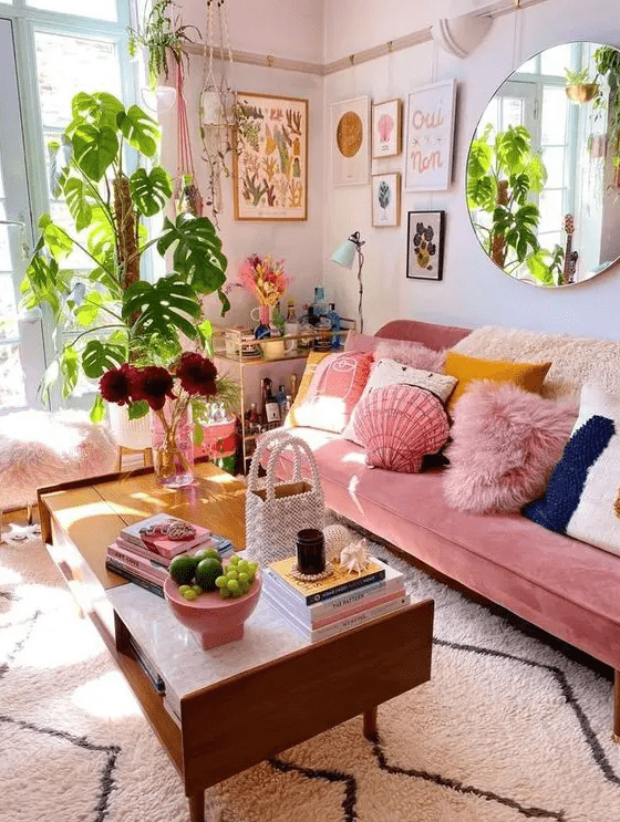 a dopamine decor with a pink sofa and colorful pillows, a coffee table, some plants and a gallery wall