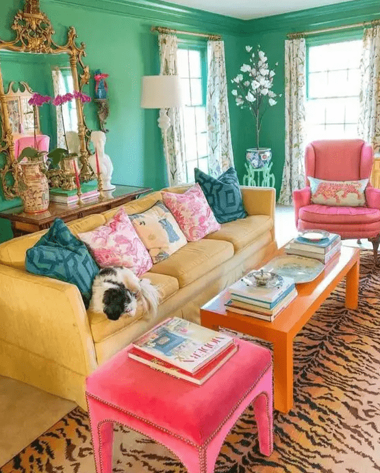 a dopamine living room with green walls, a yellow sofa, an orange table and pink chairs, a printed rug and refined decor