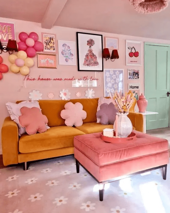 a fab dopamine decor living room with blush walls and a ceiling, a mustard sofa, a pink pouf and a crazy gallery wall
