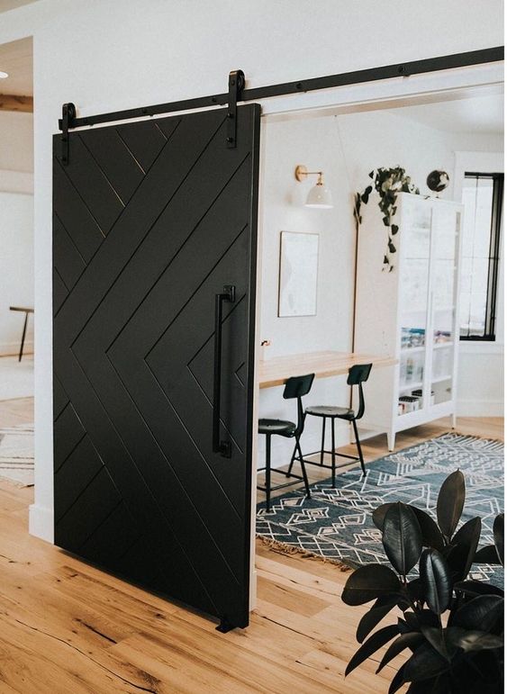 a farmhouse space accented with a black barn door that brings drama and interest to quite neutral space