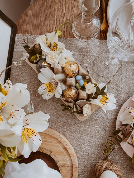 a gorgeous Easter centerpiece of an egg carton, gold foil eggs and egg shells as vases and large white blooms