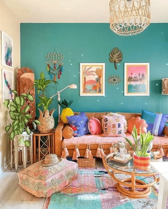 a gorgeous dopamine decor living room with a green accent wall, a pink sofa with colorful pillows, rattan tables, a bold rug and pastel artwork