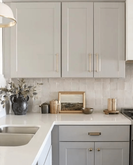a grey kitchen with a neutral zellige tile backsplash, a white stone countertop and pendant lamps is chic and lovely
