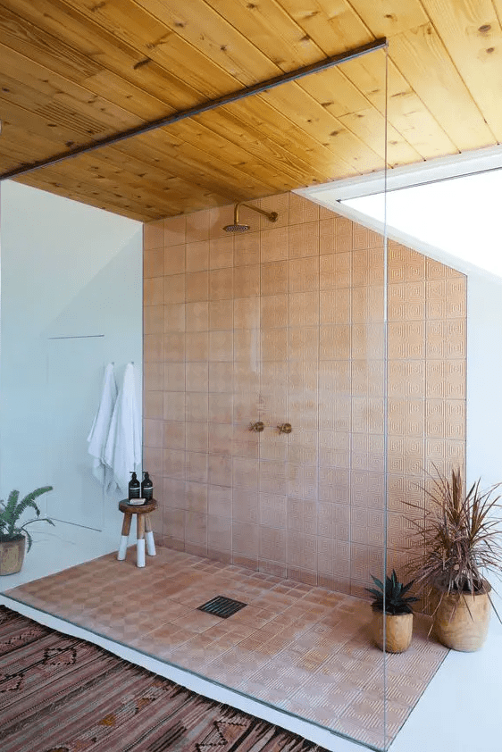 a large shower space with a wooden ceiling, terracotta tile, potted plants and natural light is amazing