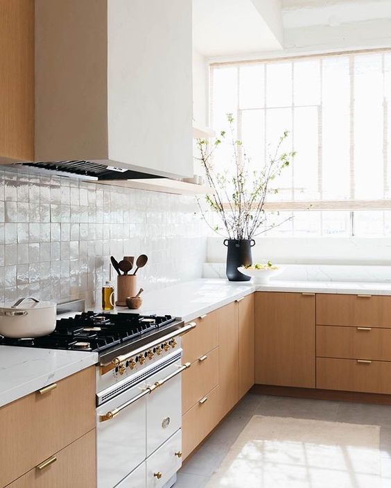a light-filled stained kitchen with a white square tile Zellige backsplash and white countertops plus a large hood