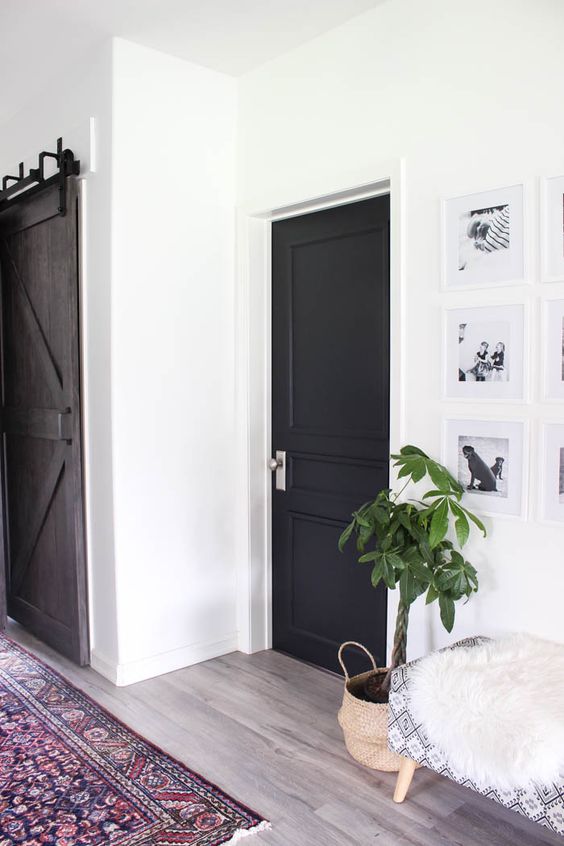 a lovely and cozy farmhouse space with a printed bench, a gallery wall and a black door plus a bright boho rug