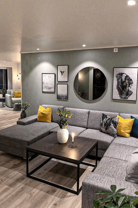 a lovely living room with a grey accent wall, a grey sectional sofa, a coffee table, a gallery wall and yellow accents