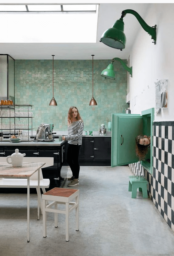 a lovely retro kitchen with black cabinets, a bold green Zellige tile wall, bold green touches and neutral dining furniture