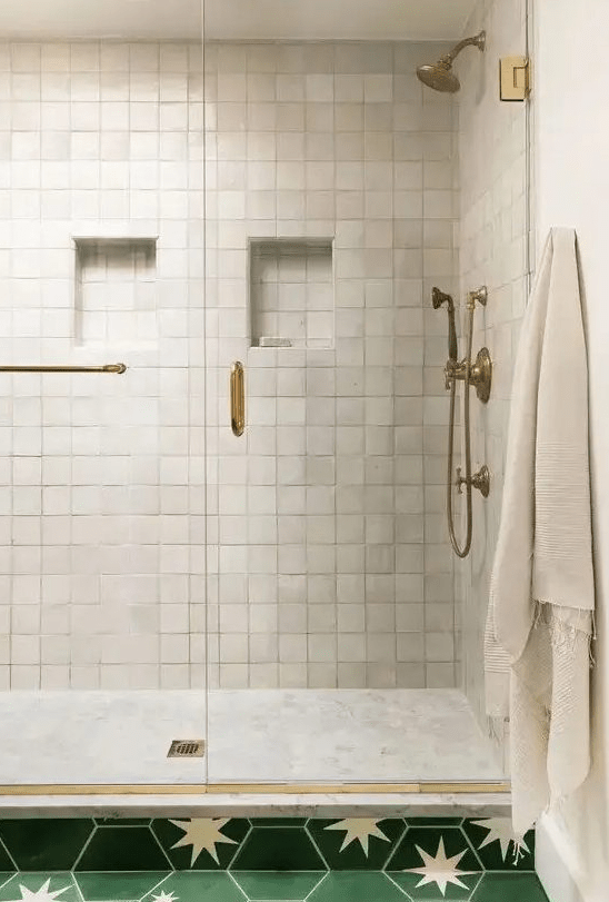 a lovely shower space clad with neutral zellige tiles and marble ones, with chic brass features for a touch of vintage in the space