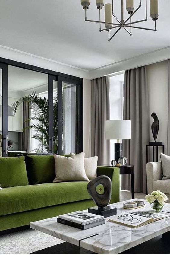 a luxurious modern living room with a green sofa and pillows, a marble coffee table, a side table witha  lamp and grey curtains