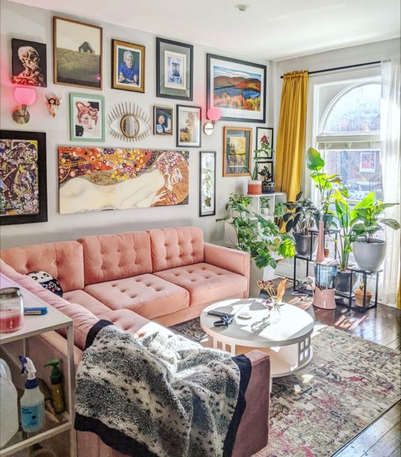 a maximalist living room with pink sofas, a bold eclectic gallery wall, a printed rug and potted plants is amazing