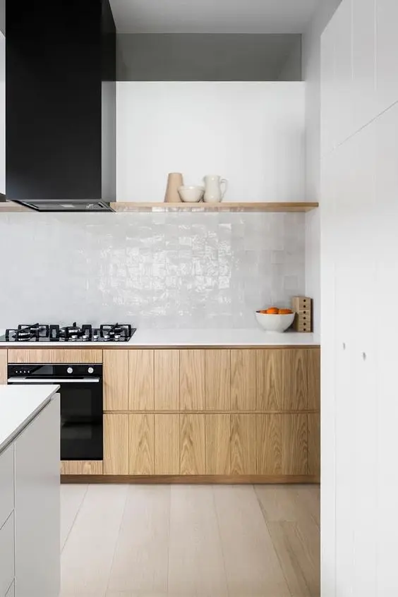 a minimalist kitchen with sleek stained cabinets, a white Zellige tile backsplash, a black hood, white countertops