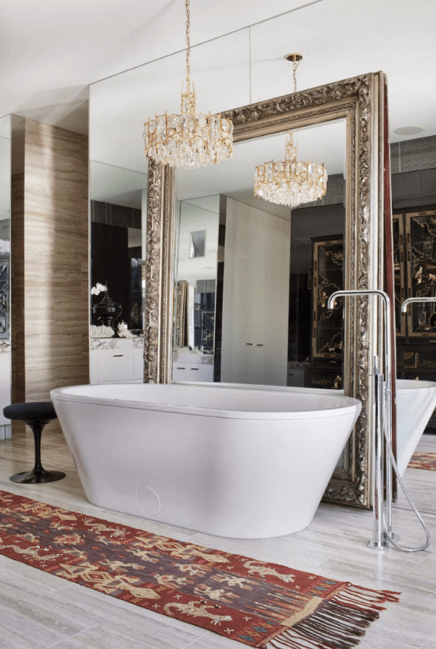 a mirror wall and an additional one in a refined frame plus a chic gold and crystal chandelier to give the bathroom a gorgeous look