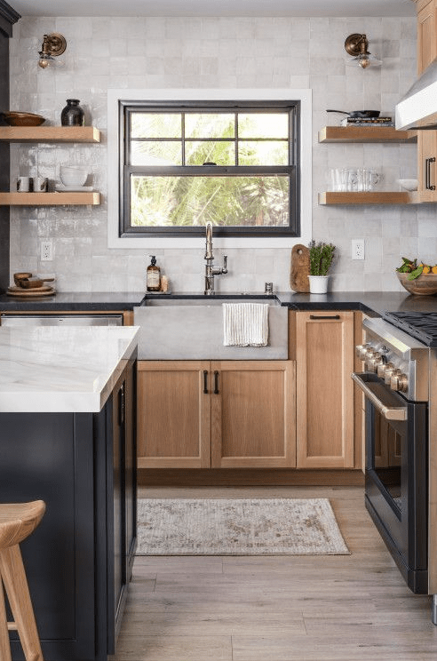 a modern farmhouse kitchen with stained cabinets, a black kitchen island, open shelves and a pearly Zellige tile backsplash