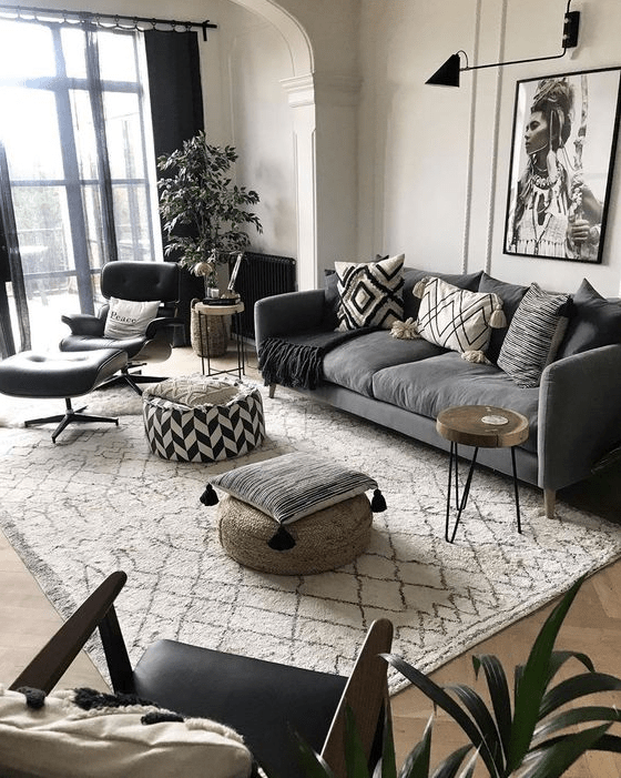 a modern meets boho living room with a grey sofa, black chairs, an artwork, a potted plant and some black touches