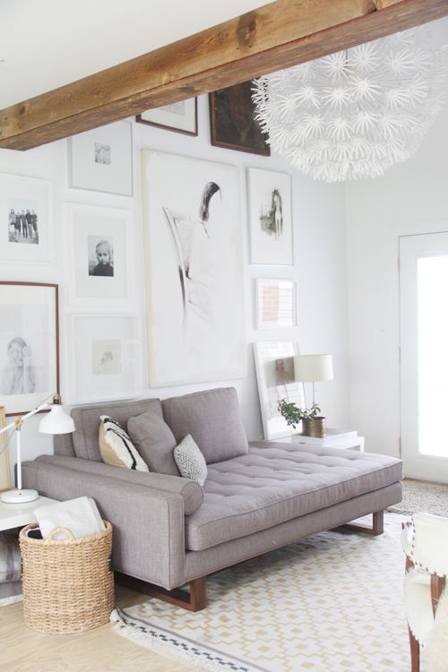 a modern serene living room with a large gallery wall, a grey sofa, a side table, a basket and a floor pendant lamp