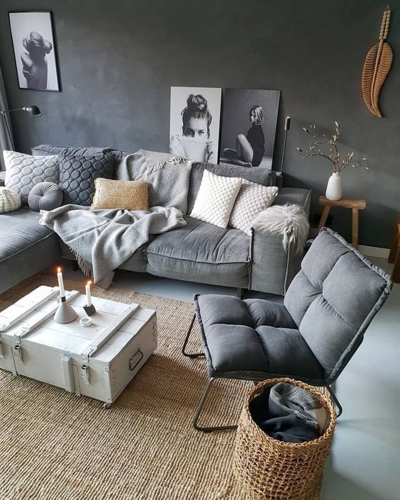 a moody Scandi living room with graphite grey walls, a grey sofa with pillows, a grey chair, a rug, a basket and a coffee table