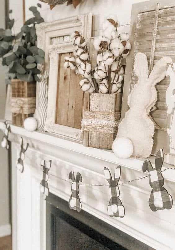 a neutral farmhouse Easter mantel with a plaid bunny garland, a fabric bunny, cotton and greenery branches in vases